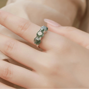 Green gemstone ring on a hand with a blurred background