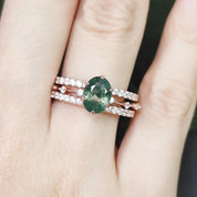 Green gemstone ring with rose gold band on a hand against a blurred natural background