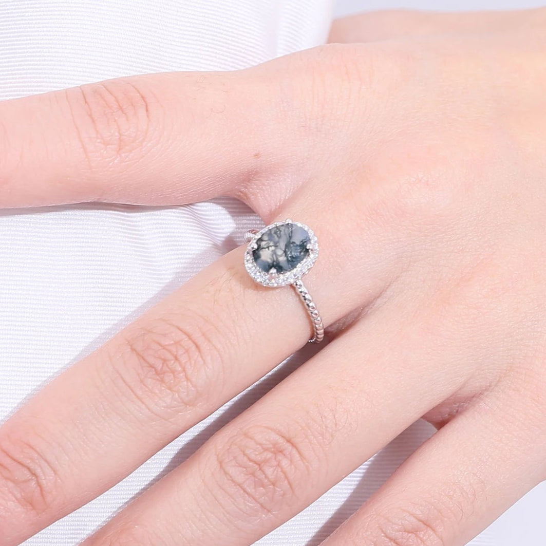 Hand wearing a ring with a blue gemstone on a white background