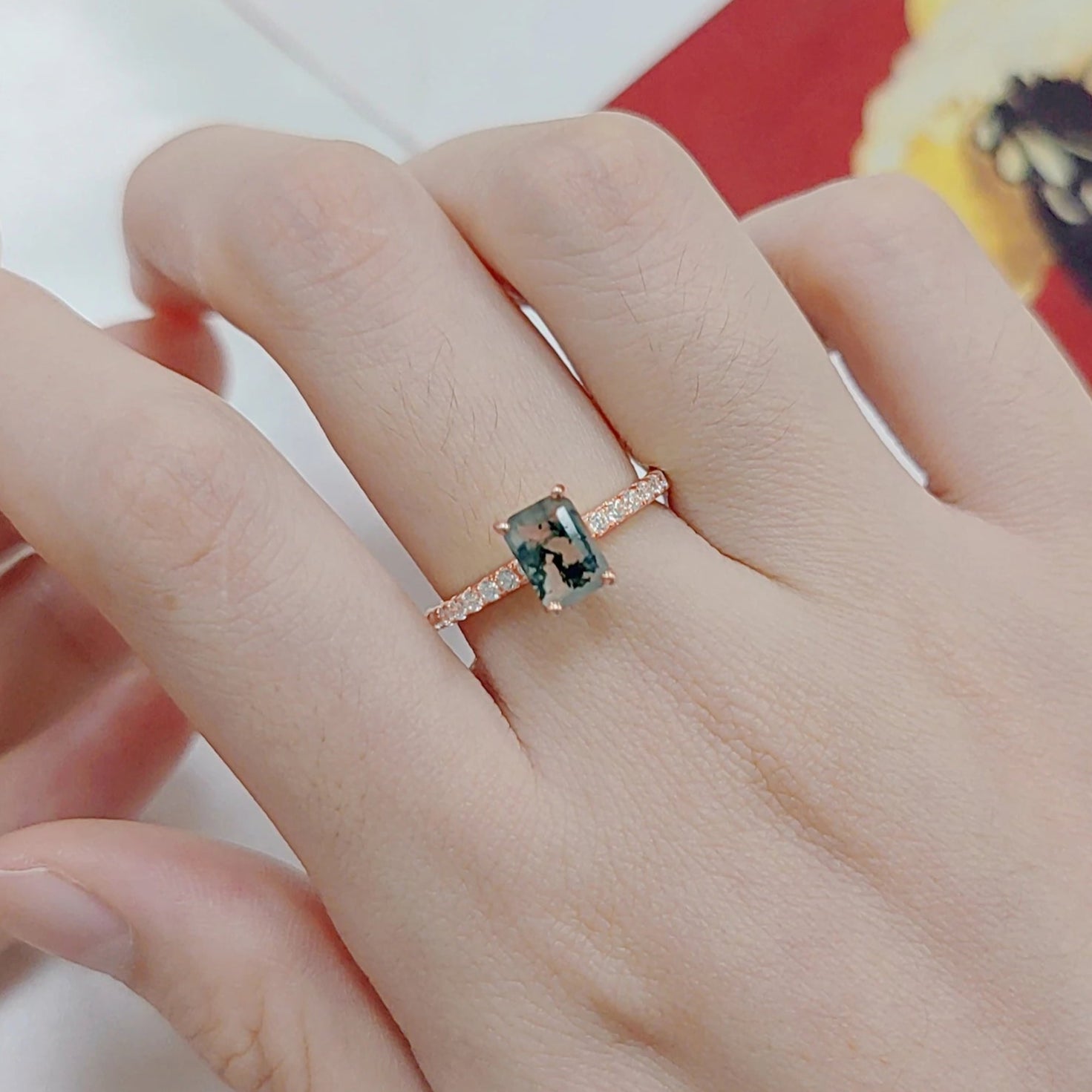 Hand wearing a ring with a gemstone on a Matisse painting background