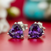 Heart-shaped purple gemstone earrings on a red background