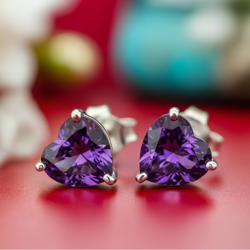 Heart-shaped purple gemstone earrings on a red background