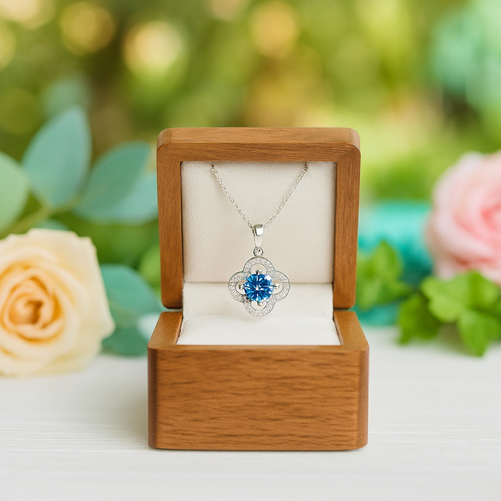 Jewelry box with a necklace featuring a blue pendant, surrounded by flowers.