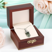 Jewelry box with a pendant inside, surrounded by flowers on a light background
