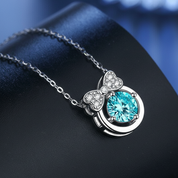 Jewelry necklace with a blue gemstone and bow design on a dark background