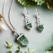 Jewelry set with green stone pendant necklace and earrings on a white background