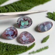 Multicolored gemstones with tweezers on a white background