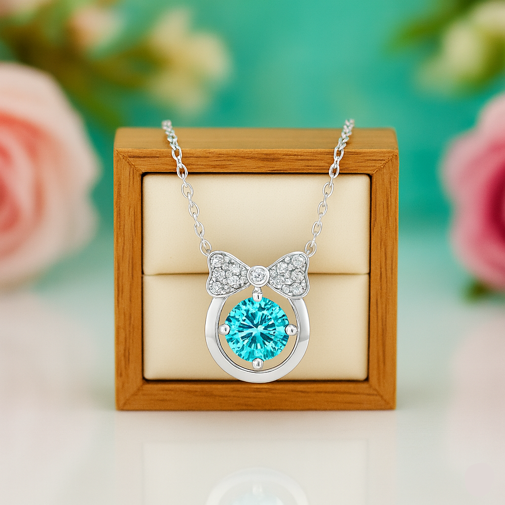 Necklace with a blue gemstone and bow design on a wooden box with flowers in the background