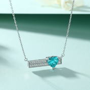 Necklace with a heart-shaped blue gemstone on a light green background