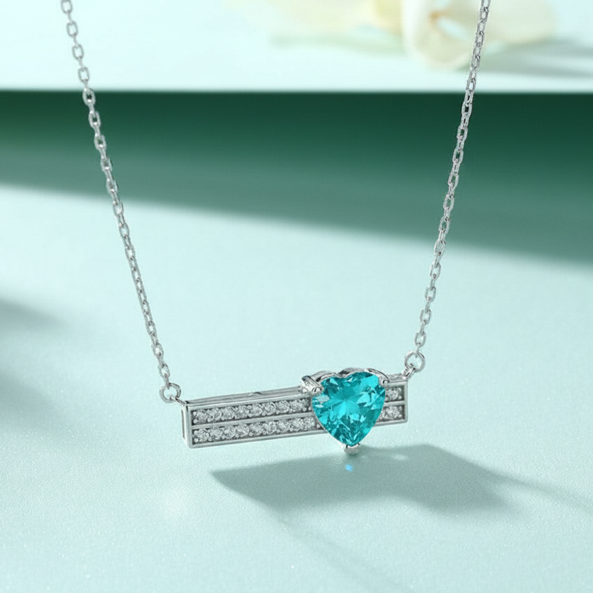 Necklace with a heart-shaped blue gemstone on a light green background
