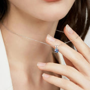 Necklace with a pendant featuring a colorful gemstone, worn by a person.