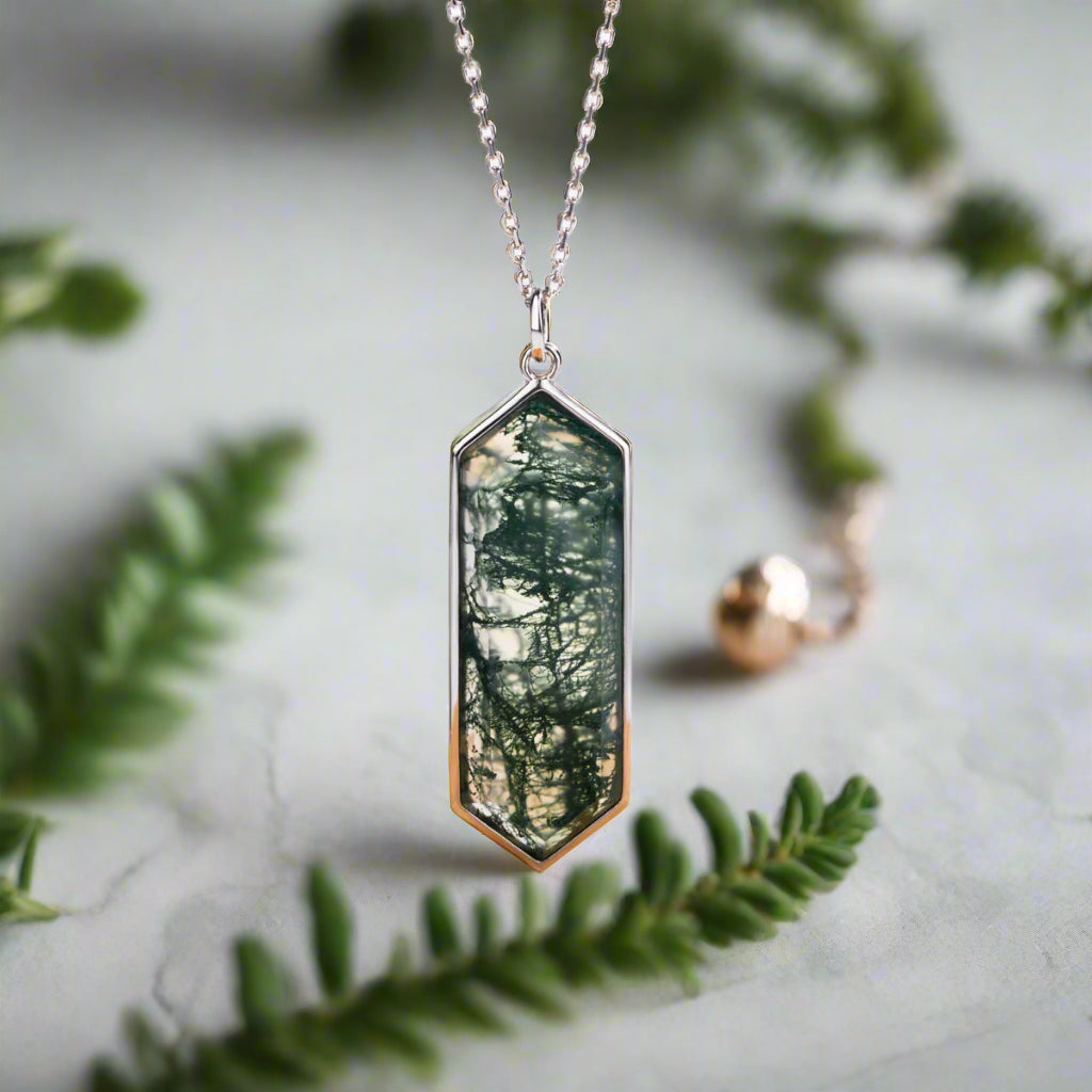 Necklace with a pendant featuring a forest scene on a wooden stand with green leaves in the background