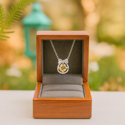 Necklace with a pendant in an open wooden jewelry box against a blurred natural background