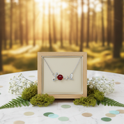 Necklace with a red stone in a wooden frame on a table with a forest background