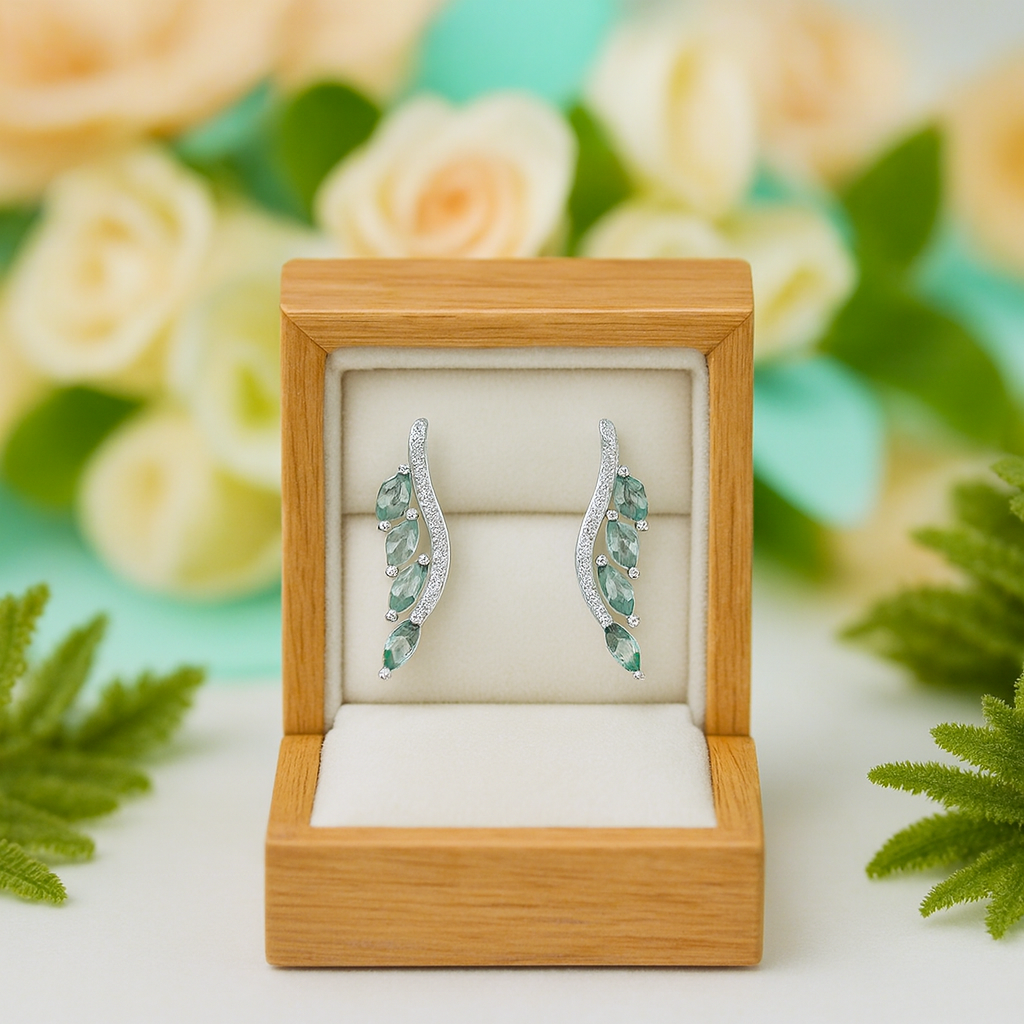 Pair of green gemstone earrings in a wooden box with flowers in the background