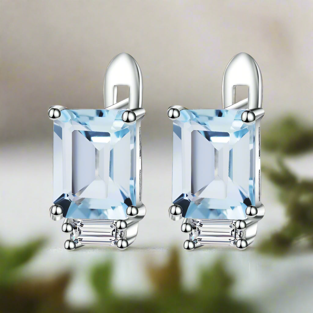 Pair of silver earrings with rectangular blue gemstones on a white background