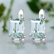 Pair of silver earrings with rectangular green gemstones on a white background