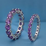 Pair of silver hoop earrings with purple gemstones on a blue background
