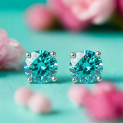 Pair of teal gemstone stud earrings on a turquoise background with pink flowers.