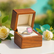 Pink ring in a wooden box with flowers in the background