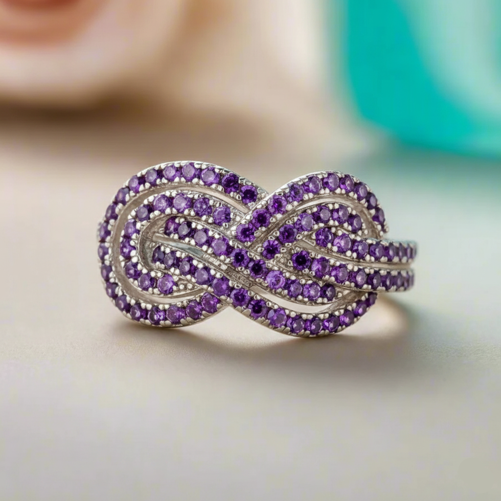 Purple gemstone ring with silver band on a neutral background