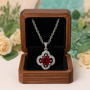 Red heart-shaped pendant necklace in a wooden box with flowers in the background