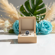Ring in an open wooden box with decorative flowers and leaves in the background