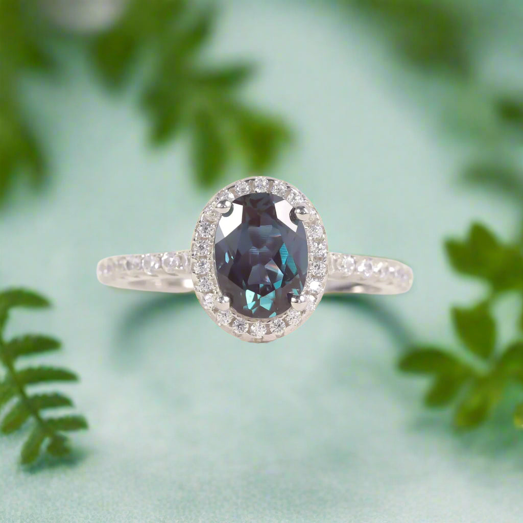 Ring with a blue gemstone and diamond halo on a soft white background