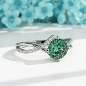 Ring with a green gemstone and diamond-studded band on a white background