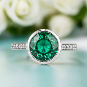 Ring with a green gemstone and diamond accents on a blurred floral background