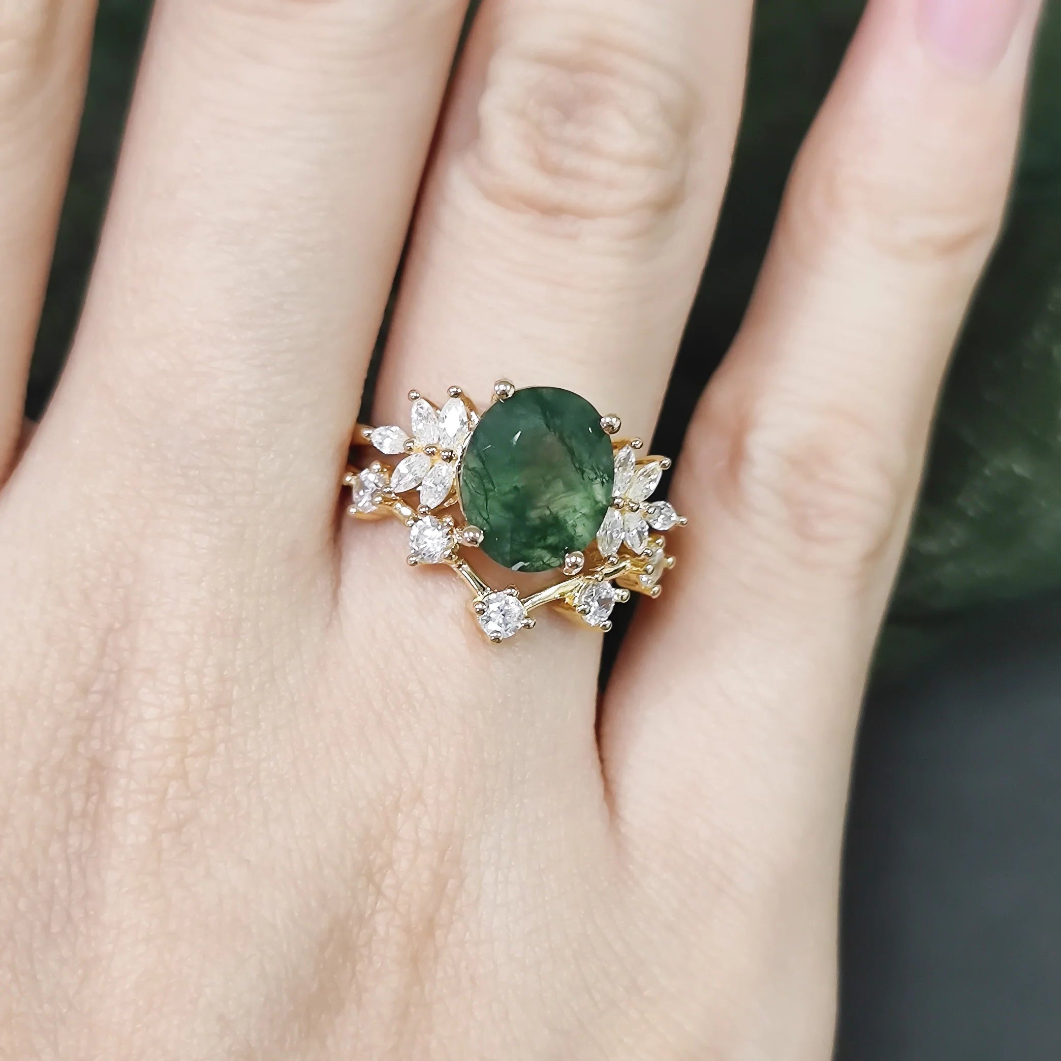 Ring with a green gemstone and gold accents on a hand