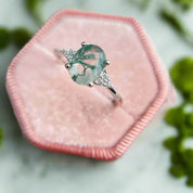 Ring with a green gemstone on a pink cushion