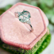 Ring with a green gemstone on a pink cushion