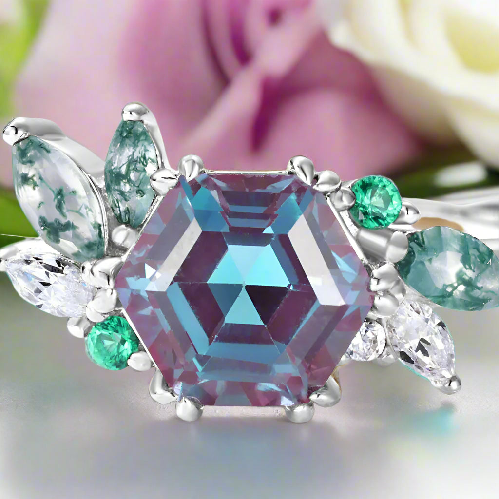Ring with a large multicolored gemstone and smaller green and clear stones on a white background