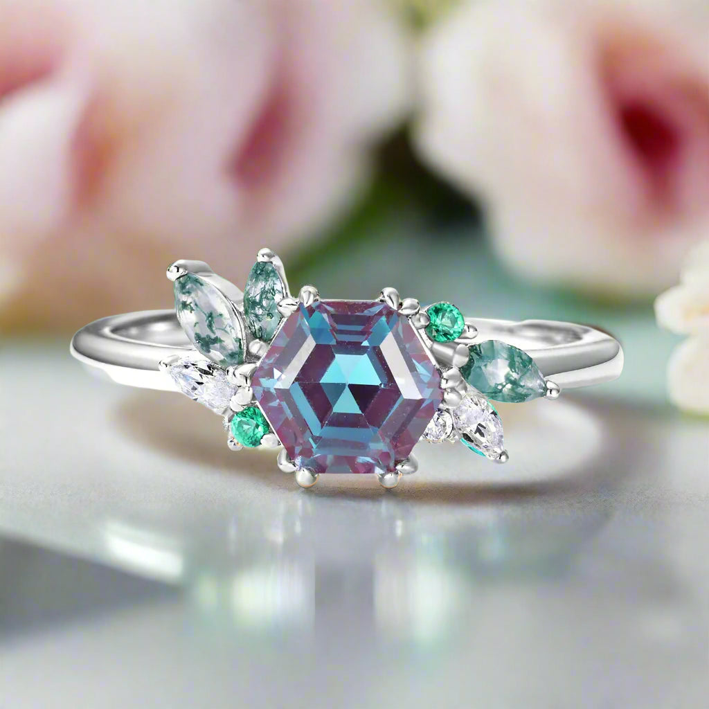 Ring with a large purple gemstone and smaller green and clear stones on a white background