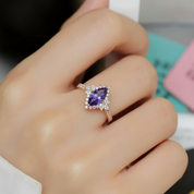 Ring with a purple gemstone on a hand against a blurred background