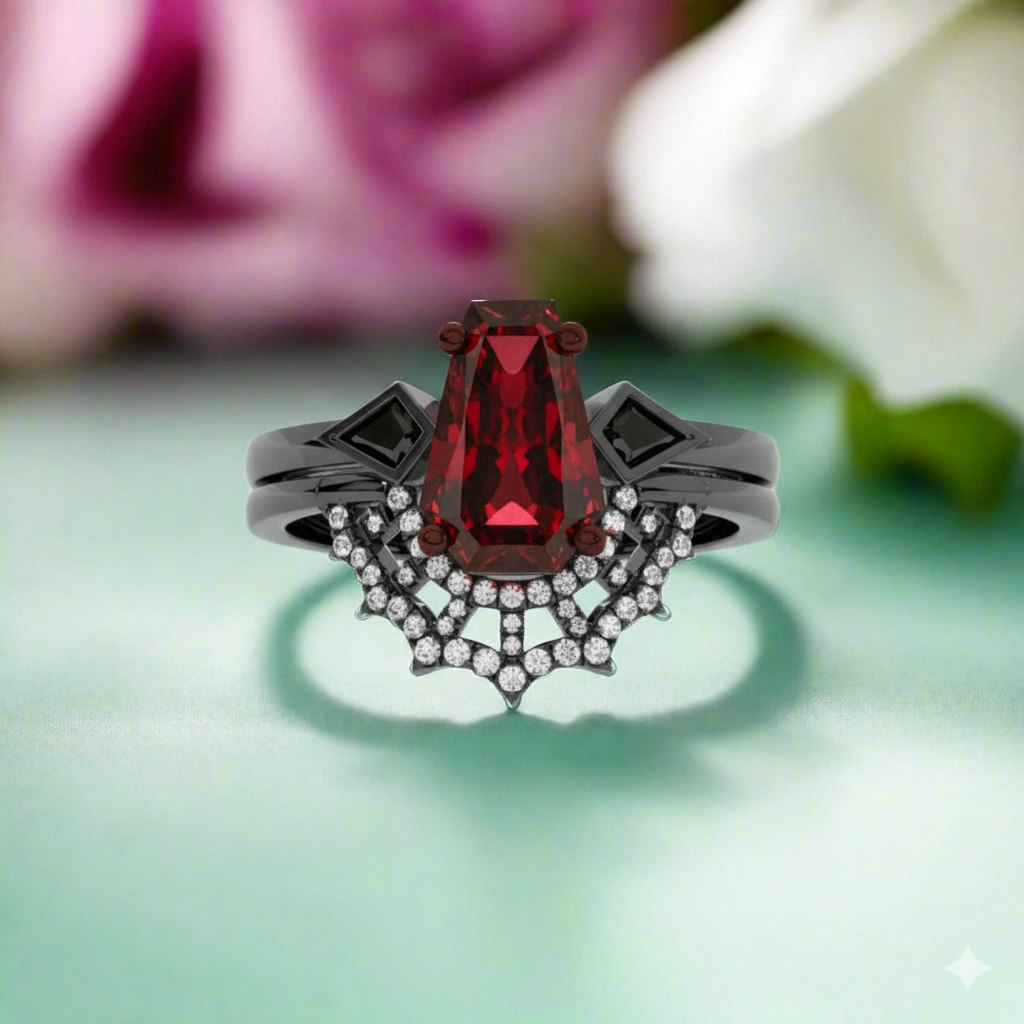Ring with a red gemstone and black metalwork on a light green background with blurred flowers.