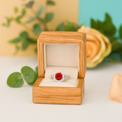 Ring with a red gemstone in a wooden box on a decorative background