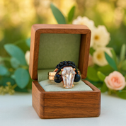Ring with black gemstones in a wooden box against a floral background