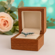 Ring with emerald stones in a wooden box with a blurred floral background