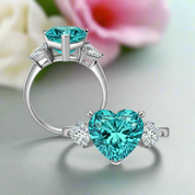 Ring with heart-shaped blue gemstone and smaller clear stones on a white background