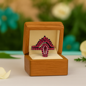 Ring with pink gemstones in a wooden box on a blurred natural background
