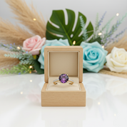 Ring with purple gemstone in a wooden box against a floral background