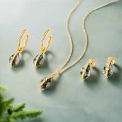 Gold necklace and earrings with green stones on a white background