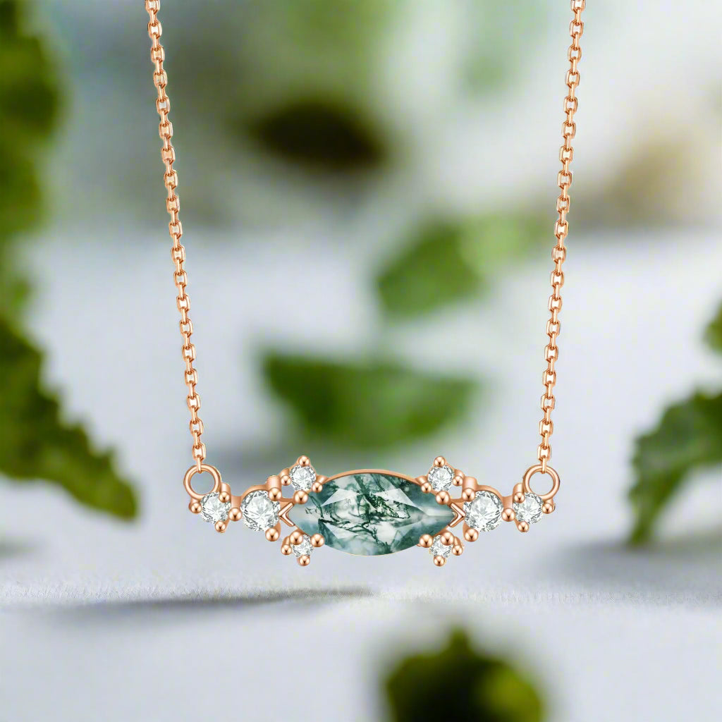 Rose gold necklace with a green gemstone and diamonds on a white background