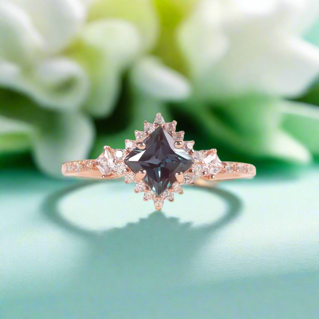 Rose gold ring with a central black diamond and smaller clear diamonds on a soft background