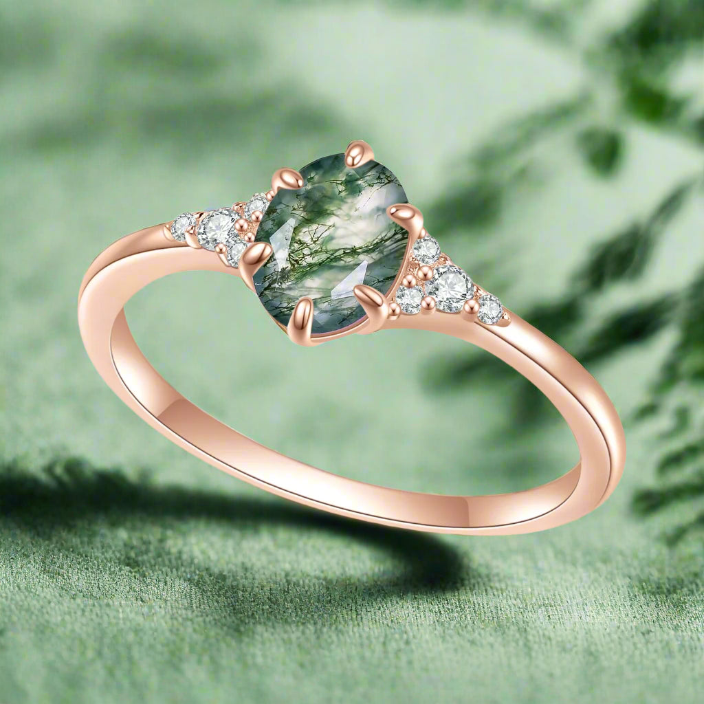 Rose gold ring with a green gemstone and small diamonds on a white background