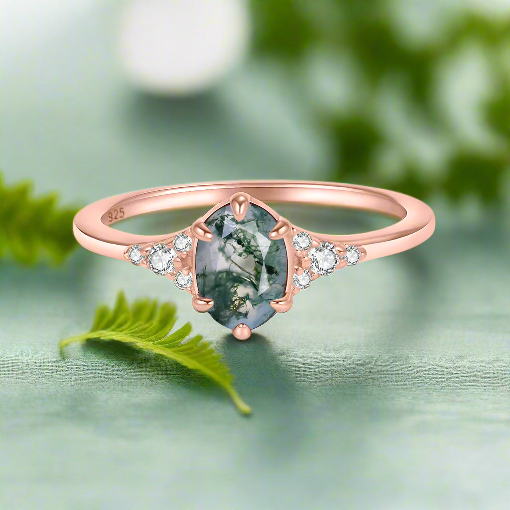 Rose gold ring with a green gemstone and small diamonds on a white background