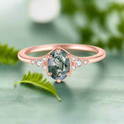 Rose gold ring with a green gemstone and small diamonds on a white background