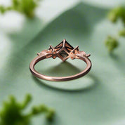 Rose gold ring with a green gemstone on a dark surface